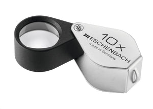 Small circular magnifier encased in black metal, with a silver coloured fold-out case with magnification written on case.