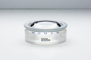 Circular magnifier with twist-to-extend feature retracted and 'menas zoom' on base of product.