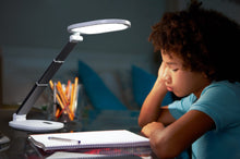 Load image into Gallery viewer, Young boy studying at a desk with Daylight&#39;s Foldi Go.
