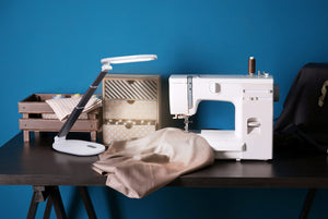 Daylight's Foldi Go on a desk with a sewing machine. 