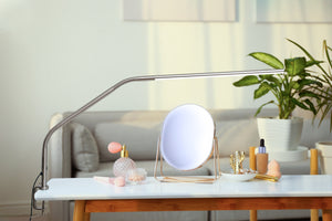 Slimline table lamp on a coffee table, being used for makeup application. 
